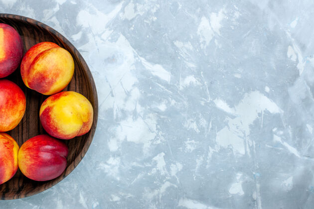 柑橘顶视图新鲜桃子醇厚可口的水果内棕色盘子在浅白色的办公桌上水果食品醇香