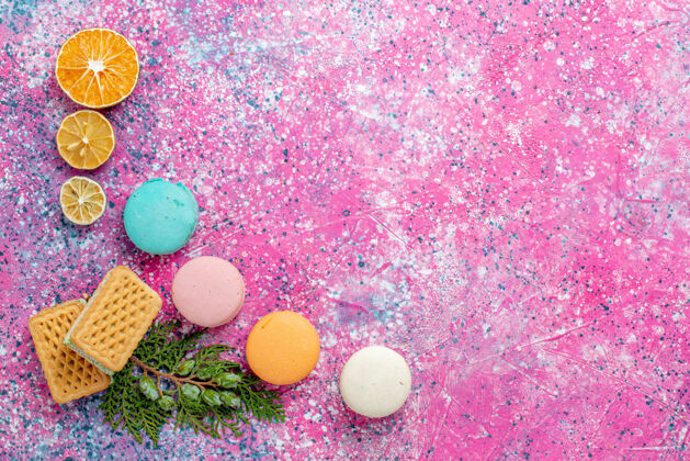 鸡蛋顶视图五颜六色的法国马卡龙 粉色桌上有华夫饼蛋糕 甜甜的烤派 饼干糖游戏设备蛋糕糖