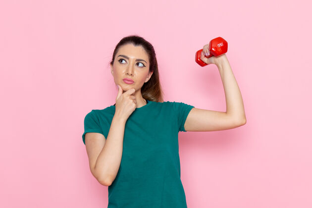 运动正面图年轻女性在粉红色的墙上做运动和举哑铃运动员运动锻炼健康锻炼锻炼微笑人