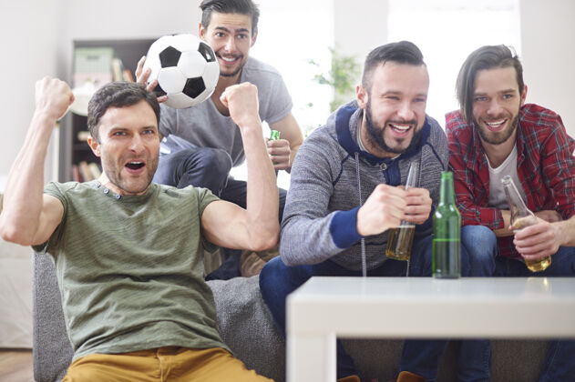 看电视一群年轻人在电视上看比赛情绪足球举手