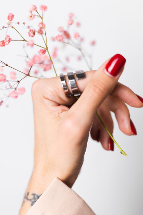美甲柔美温柔的照片 女人手上戴着大戒指 红色的指甲 手上拿着可爱的粉色干花开花皮肤花店