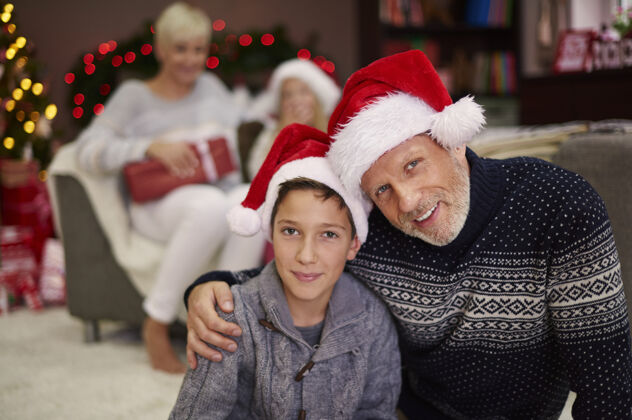 父亲戴圣诞帽的父子画像圣诞装饰品背景的人无辜