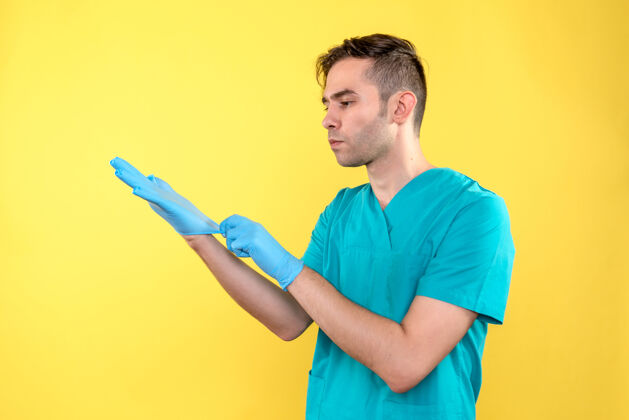 情绪黄色墙上戴着蓝色手套的男医生的正视图男性医生男性穿着