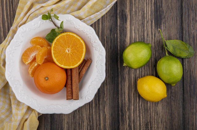 木头顶视图剥皮的橙色楔子和肉桂放在盘子里 柠檬和柠檬放在木制背景上橘子柠檬盘子