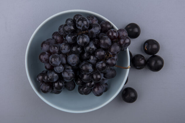 树懒水果的顶视图 如碗中的葡萄和灰色背景上的树莓顶部水果浆果