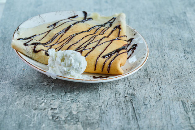 奶制品薄煎饼配香草冰淇淋 巧克力放在大理石表面的白色盘子上美味奶油美味