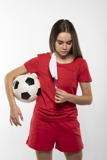 足球制服戴着面具拿着球的女足球运动员持球面罩年轻