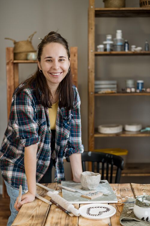 陶瓷微笑的女人站在她的陶器车间工艺创意工作场所