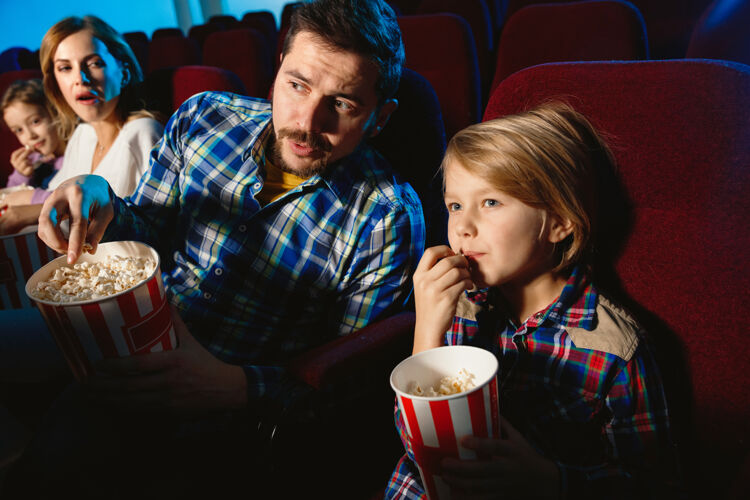 娱乐年轻的白种人家庭在电影院 房子或电影院看电影看起来富有表现力 惊讶和情绪化独自坐着玩关系 爱情 家庭 童年 周末时间大厅看看