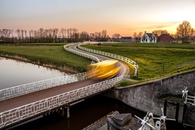 白天在一个绿色社区的运河上的一座桥的风景照片景色阳光云