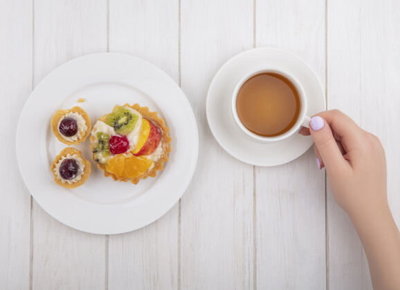 鞑靼俯视图：一位女士在白色背景的盘子上喝着一杯有馅饼的茶白的早晨饮用