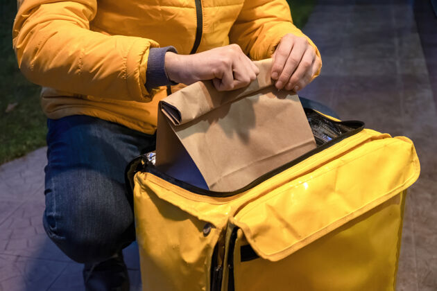 戒指一个穿着黄色夹克的送货员打开黄色背包 拿着一个带订单的袋子发货安全客户