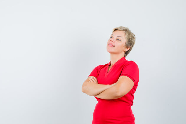 女性穿红色t恤的成熟女人交叉着双臂站着 看起来很沉思红色沉思站