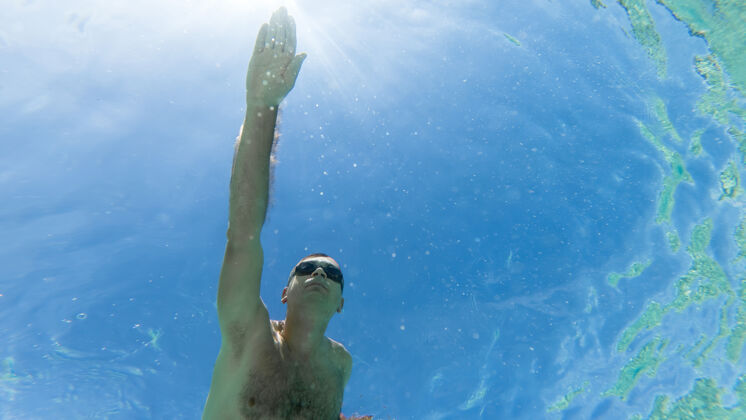 运动员白种人戴着泳镜在水下游泳 蓝色透明的水水下发现比赛