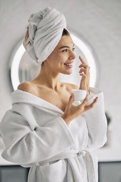 浴袍笑脸女人拿着护肤霜女人清洁自然