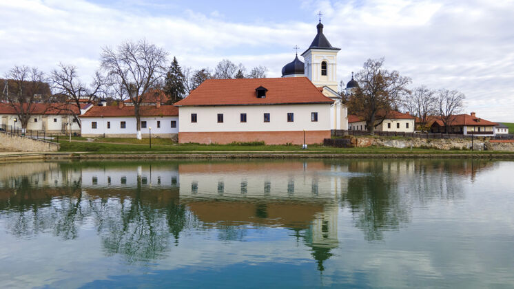 东正教卡普里亚纳修道院的景色石头教堂 建筑物 光秃秃的树木前景是一个湖泊 摩尔多瓦的好天气小教堂文化修道院