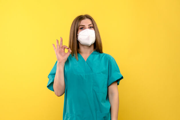 流行黄色地板上戴口罩的女医生正面图病毒大流行医院感慨微笑医院肖像