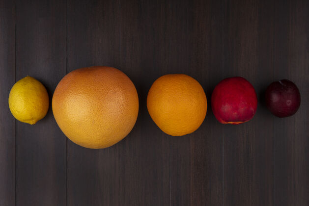 桃木制背景上的柠檬 橘子 柚子 桃子和李子的俯视图柠檬柚子水果