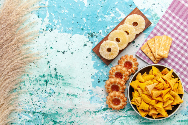 晚餐顶视图小辣薯片饼干干菠萝环和饼干浅蓝色背景薯片零食颜色脆卡路里卡路里背景菠萝
