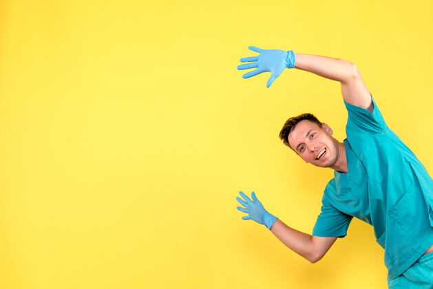 活跃黄墙上男医生戴着蓝手套摆姿势的正面图黄色男医生女人