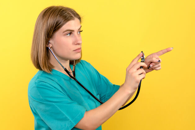 听诊器黄色墙上带眼压计的女医生的正视图黄色压力医生