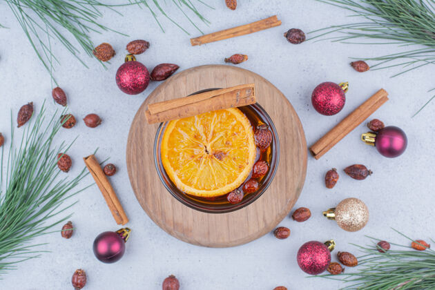圣诞饰品玫瑰果和圣诞球放在大理石表面的茶棍子橘子切片