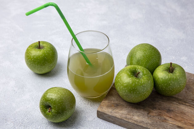 苹果侧视图绿色苹果与苹果汁在一个玻璃杯和绿色吸管上的白色背景食品水果玻璃