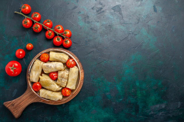番茄俯瞰美味的肉食卷心菜里面卷着新鲜的西红柿在深蓝色的桌子上肉食晚餐卡路里蔬菜菜烹饪观点菜肴深蓝色