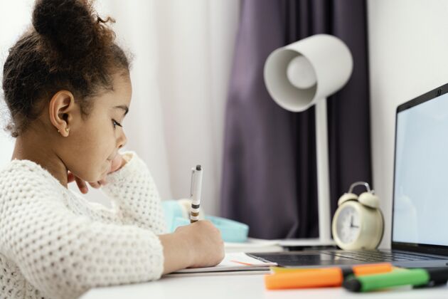 课程小女孩在家使用笔记本电脑上在线上学的侧视图网络学习孩子