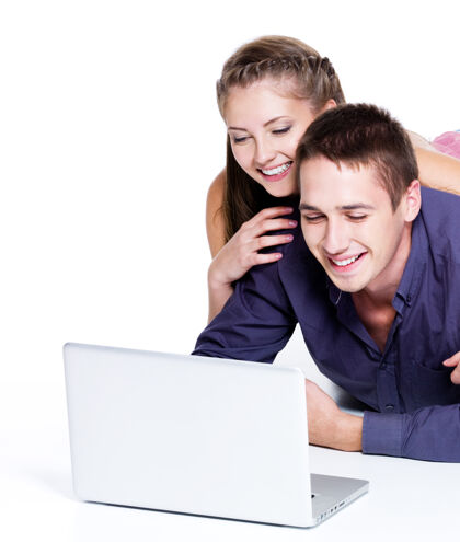 在线一对幸福的微笑着的情侣饶有兴趣地看着笔记本电脑-孤立的白色用户休闲年轻