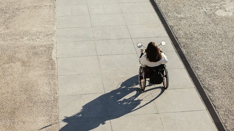 紊乱高角度的女人在街上坐轮椅残疾女户外