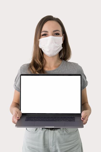 笔记本电脑戴着面具拿着笔记本的女人冠状病毒流行病女人