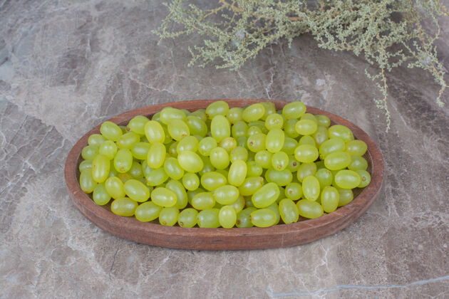 碗一束绿色的葡萄放在木盆里 里面有植物水果新鲜自然