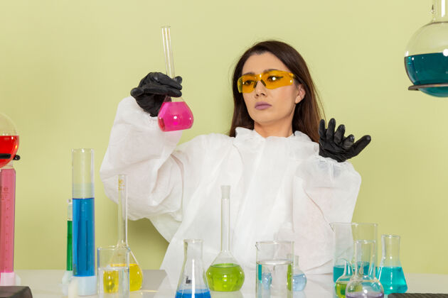 工作前视图穿着特殊防护服的女化学家在绿色表面上处理溶液女性防护特殊
