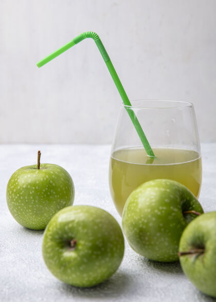 稻草前视图绿色苹果与苹果汁在一个玻璃杯和绿色吸管上的白色背景绿色新鲜食品