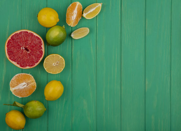 新鲜顶视图复制空间半葡萄柚与去皮的橙子和柠檬酸橙片上的绿色背景水果绿色柠檬