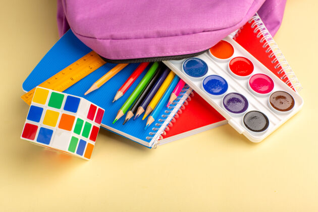 盒子前视图彩色铅笔与抄写本油漆和浅黄色书桌上的紫色袋子容器钢笔正面