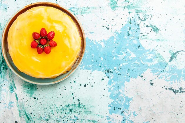 雪俯瞰美味的蛋糕 黄色糖浆和红色草莓放在蓝色桌子上饼干蛋糕烤甜饼糖茶冷新鲜烘焙