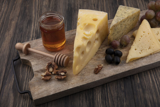 食物侧视图蜂蜜在一个罐子与不同的奶酪和核桃与葡萄的立场奶酪罐子甜味