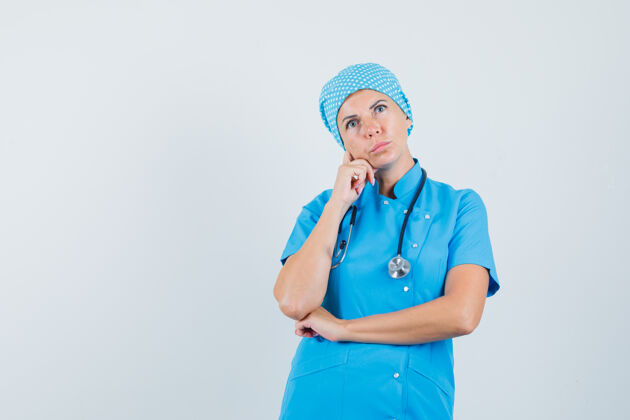成人女医生穿着蓝色制服抬头 神情沉思前视图女人年轻人服务