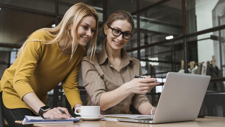 团队年轻的笑脸女商人在办公桌上用笔记本电脑工作横向职业女性