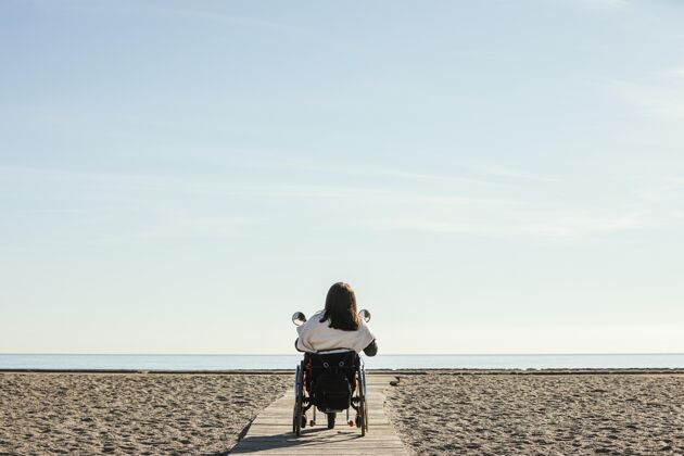 轮椅海滩上坐轮椅的女人的后视图海滩条件户外