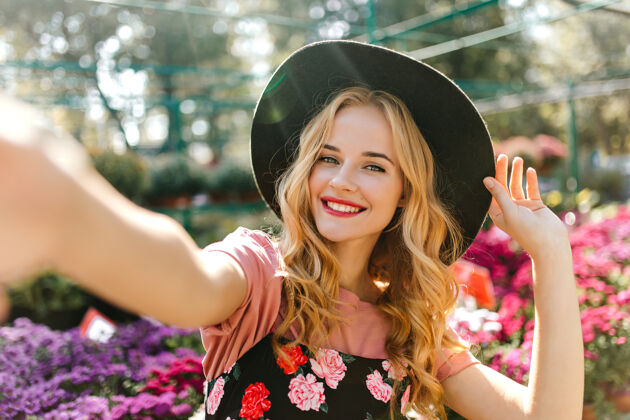 温室美丽的眼睛在橘子园里自拍的漂亮女人戴着黑帽子和花摆姿势的快乐女人花束卷发公园
