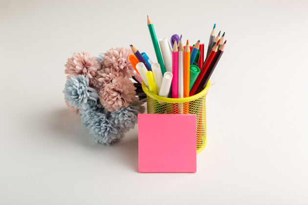 彩虹白色书桌上的彩色铅笔和鲜花学校花卉绘画