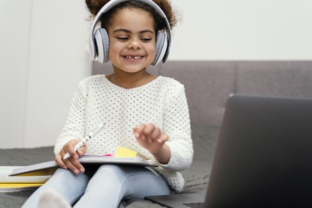 孩子笑眯眯的小女孩用笔记本电脑上网上学孩子学习课程