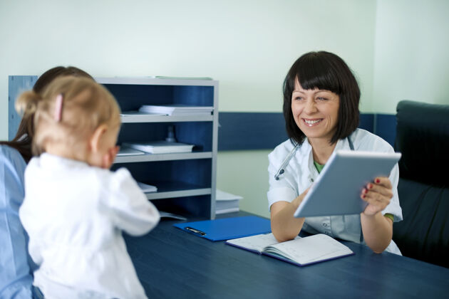 会议医生在平板电脑上显示母亲的医疗结果快乐制服疾病