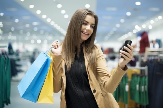 零售开朗的女购物者在手机上发短信表情购物中心