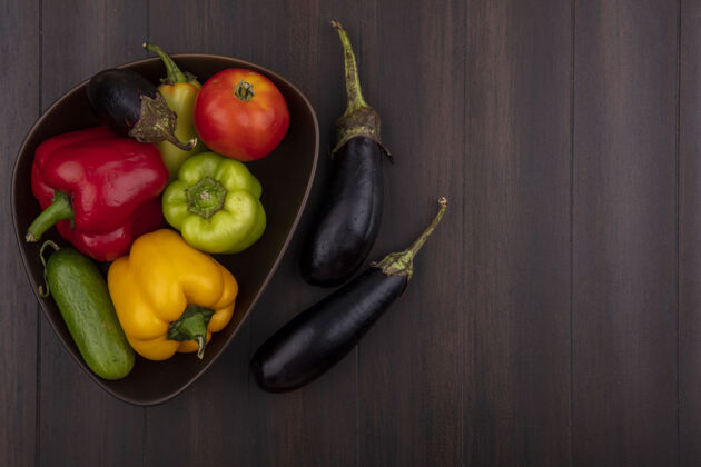 食物顶视图复制空间彩色甜椒与黄瓜和西红柿在碗与茄子在木制背景上黄色蔬菜顶部