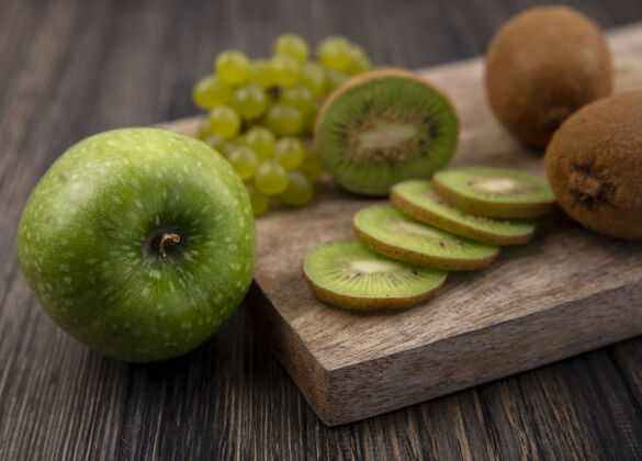 绿色侧视图猕猴桃片与绿色葡萄站在一个绿色的苹果在一个木制的背景切片景观壁板