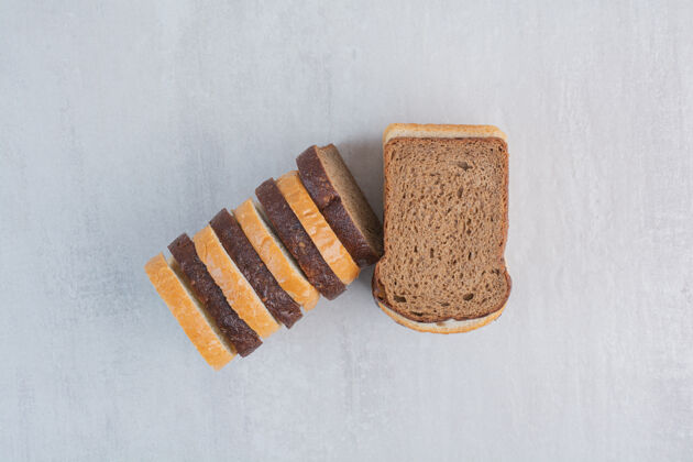 面包房新鲜的白色和棕色面包片放在大理石背景上烘焙食品面包片